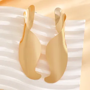 Detailed view of minimalist irregular gold twisted metal earrings with a polished finish
