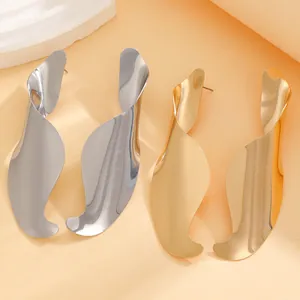 Detailed macro view of large irregular twisted wavy earrings in gold and silver finish