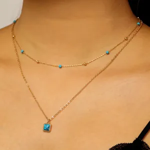 Detailed view of layered bohemian gold necklace with turquoise beads and square pendant