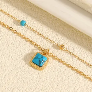Close-up of bohemian layered gold necklace with square turquoise pendant