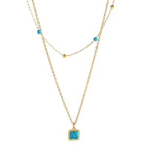 Detail of bohemian double-layer gold necklace featuring a square turquoise stone pendant.
