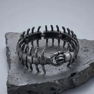 Detailed view of a punk-style centipede titanium steel bracelet on a volcanic rock.