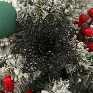 Detailed view of a black glittery hollow poinsettia flower on a snowy pine branch