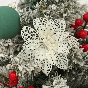 Macro shot of a white glittery hollow poinsettia flower on a snowy Christmas tree