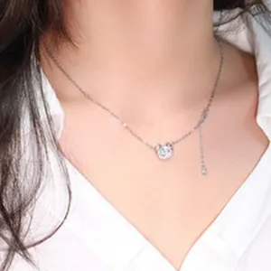 Close-up of a silver-toned clavicle chain with a sparkling round pendant on a model