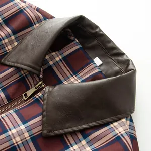 Primo piano di una giacca scozzese vintage con colletto in pelle marrone e zip di alta qualità