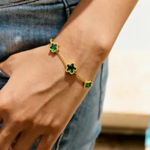 Detail shot of a gold titanium steel bracelet with three green star-shaped gemstones.
