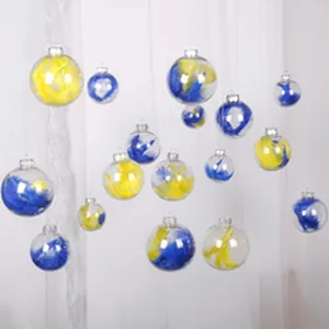 Dettaglio di palline di Natale in acrilico trasparente con piume blu e gialle vivaci.