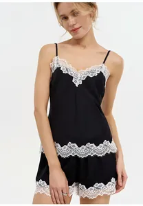Detailed view of black satin pajama set with white floral lace trim on camisole and shorts.