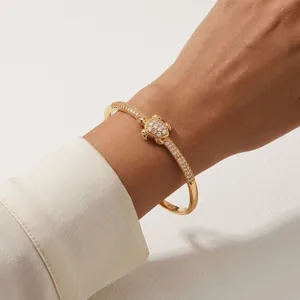 Gros plan détaillé d'un bracelet tortue doré orné de zircons étincelants sur un poignet.