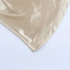 Detailed macro view of champagne gold satin fabric and neat hem stitching for elegant dress.