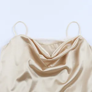 Detail of champagne satin slip dress featuring elegant cowl neck and white lace trim.