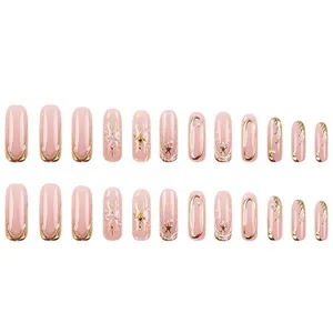 Detailed view of pink French press-on nails featuring 3D gold accents and tiny pearls.
