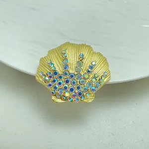 Close-up of vintage golden shell brooch featuring iridescent rhinestones and fine texture