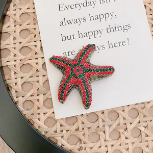 Detailed macro shot of a vintage starfish brooch with red and green rhinestones.