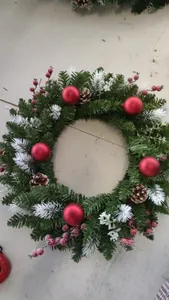 Macro detail of a festive Christmas wreath featuring pine cones and red ornaments