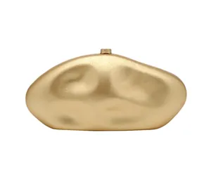 Nahaufnahme einer goldenen, unregelmäßigen skulpturalen Abendtasche mit mattem Metallic-Finish