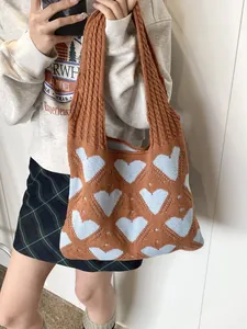 Stylish brown and blue heart pattern knitted shoulder tote bag for women shown on model