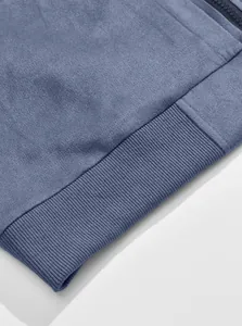 Makro-Detail einer blauen Wildleder-Bomberjacke mit feiner Stoffstruktur und Rippsaum.