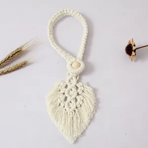 Dettaglio del fermatende in macramè boho fatto a mano con design a foglia e legno