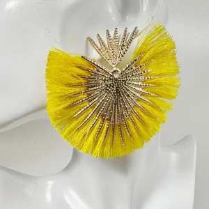 Gros plan de boucles d'oreilles vintage en éventail doré avec pompons jaunes sur mannequin.