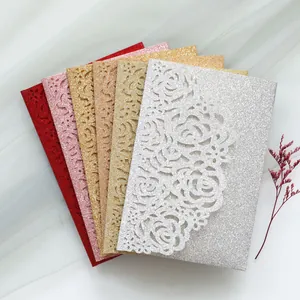 Gros plan d'invitations de mariage pailletées découpées au laser avec motif de roses.