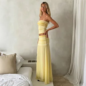 Full-length view of a chic yellow striped tube top and sheer mesh maxi skirt set
