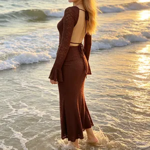 Détail d'une robe longue en dentelle marron dos nu avec lacets sur une plage au coucher du soleil