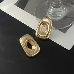 Detailaufnahme von goldenen unregelmäßigen geometrischen Ohrringen mit Metalloberfläche