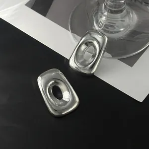 Nahaufnahme von unregelmäßigen silbernen Metallohrringen mit glatter, verzerrter Oberfläche