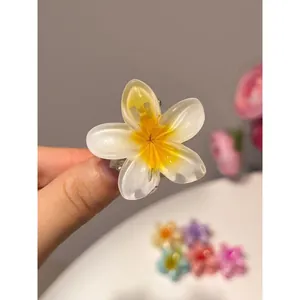 Vue détaillée d'une pince à cheveux en forme de fleur de frangipanier jaune et blanc