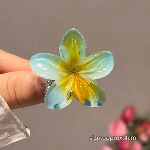 Détail macro d'une pince à cheveux fleur de frangipanier bleue et jaune de 4 cm