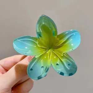 Gros plan d'une pince à cheveux frangipanier avec dégradé bleu et jaune translucide.