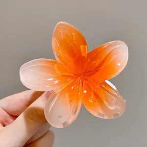 Gros plan d'une pince à cheveux en forme de fleur de frangipanier dégradé orange vif