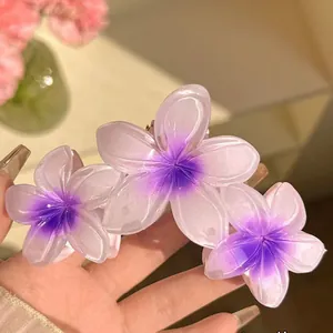 Vue détaillée des fleurs de frangipanier dégradées violettes sur une pince à cheveux.