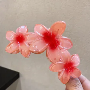 Gros plan d'une pince à cheveux fleur de frangipanier rose avec finition brillante