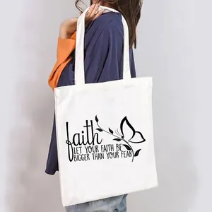 Close-up detail of a white canvas tote bag featuring an inspirational butterfly faith print.