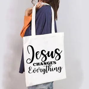 White canvas tote bag with Jesus Changes Everything print shown on model shoulder