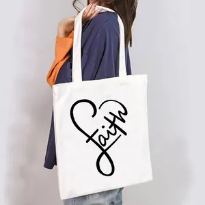Detailed view of a stylish white canvas tote bag featuring a black artistic Faith heart print