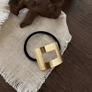 Detail view of a minimalist hair tie with a square gold brushed metal element