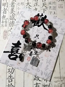 Detail view of a Chinese style red and black beaded bracelet with butterfly charm