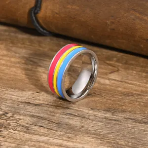 Detailed macro view of a silver stainless steel ring with red, yellow, and blue enamel stripes