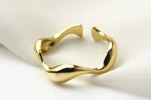Makroansicht eines vergoldeten unregelmäßigen welligen offenen Rings mit glatter Politur.