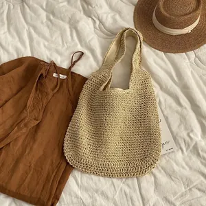 Detailansicht einer gewebten Strohtasche auf weißem Bett mit Urlaubsaccessoires
