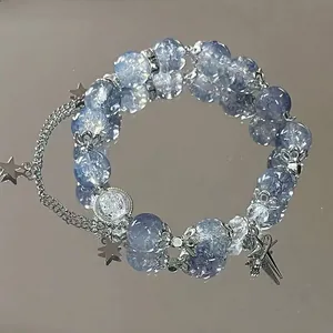 Close-up of blue ice-crackle beaded bracelet with silver star and cross charms.