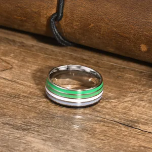 Close-up of a striped enamel ring with green, white, gray, and black colors on a wood surface