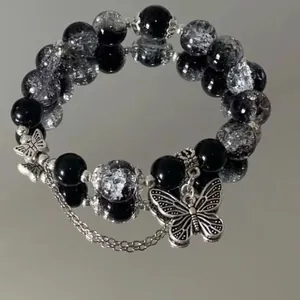 Black and white crackle glass beaded bracelet with silver butterfly charm on mirror