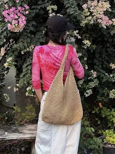 Lifestyle-Detail einer großen handgewebten Strohtasche für den Sommer-Strandurlaub