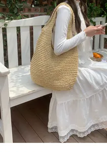 Handgefertigte Strandtasche aus Stroh mit großem Fassungsvermögen, getragen von einem Model