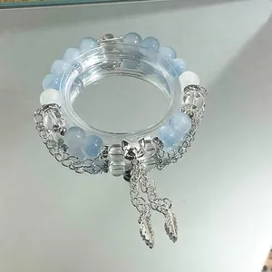 Close-up of light blue beaded bracelet featuring silver fox head and feather charms